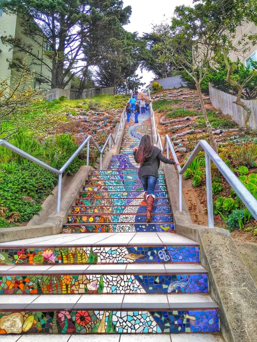 what to do in San Francisco in a day - tiled steps People ascending the colorful and artistic 16th Avenue Tiled Steps in San Francisco, surrounded by greenery and trees.