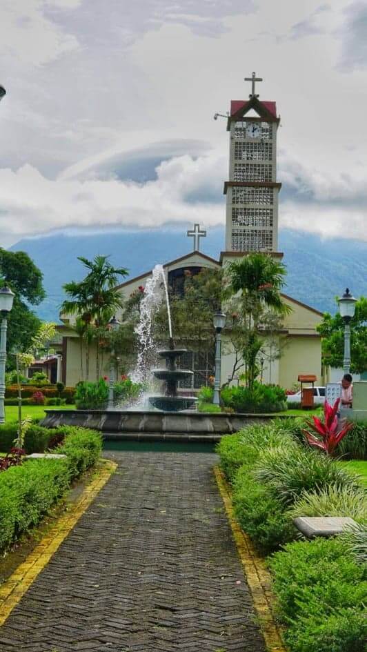 Arenal Volcano in background of church with clouds looming in La Fortuna