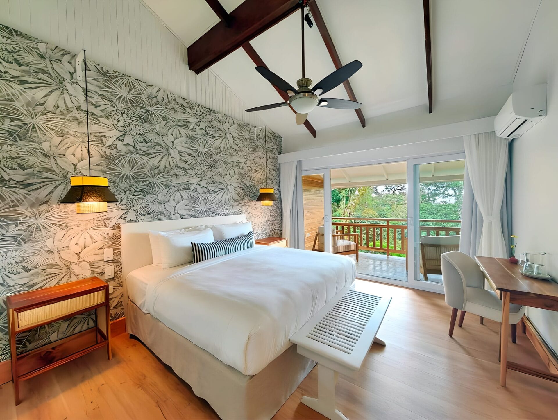 Modern hotel room with a king bed, tropical-themed wallpaper, wooden features, and a balcony at Monteverde Lodge in Monteverde, Costa Rica.