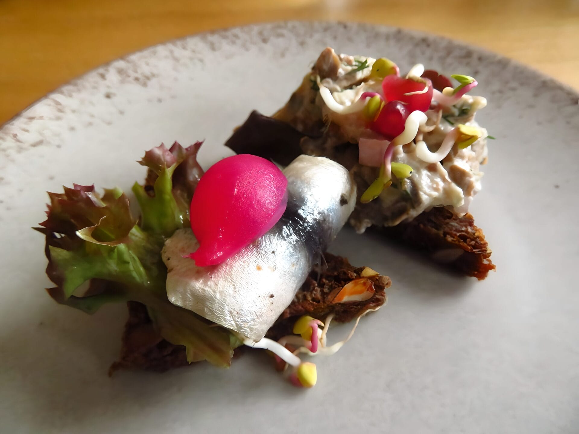 Appetizing Estonian dish with sprat, rye bread, pickled vegetables, and sprouts on a plate in Tallinn, Estonia.