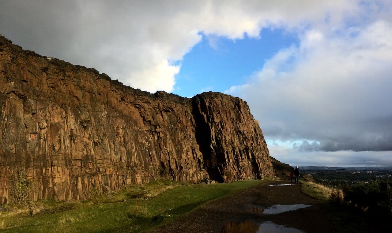 Rocky cliffs against a dramatic sky at Arthur's Seat in Edinburgh, Scotland.