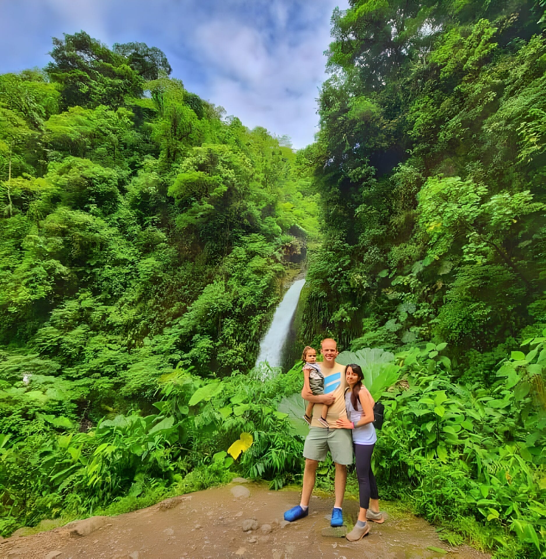 A family posing in front of a waterfall surrounded by lush greenery in Costa Rica.